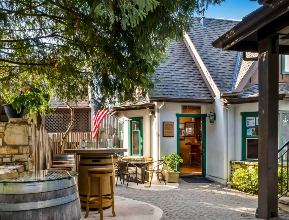 Outdoor patio of a winery with barrel tables and a building entrance.